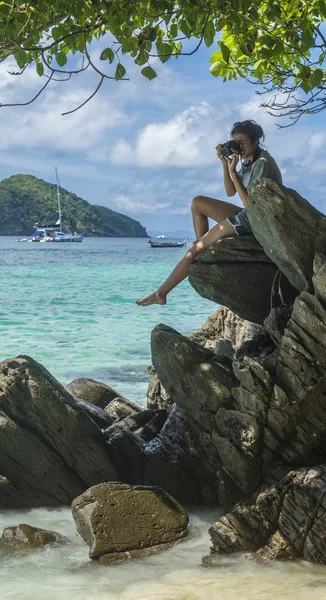 Mulher sentada na rocha com câmera fazendo fotos. Bela vista do mar cristalino e areia branca da ilha tropical, Koh He, Tailândia — Fotografia de Stock