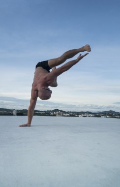 Yakışıklı genç adam çıplak gövde ve hareketleri bir çatıda gökyüzü arka plan üzerinde dans fren yaparken güneş gözlüğü
