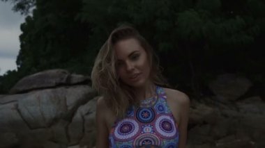 Güzel sarışın kadın bulutlu yaz gündüzleri deniz kenarında kayalar arasında