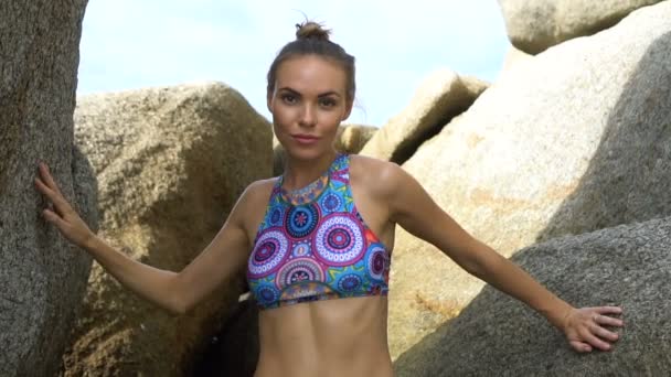 Mujer rubia bonita entre las rocas cerca del mar durante el hermoso día de verano — Vídeo de stock