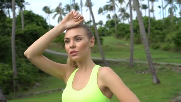 Fitness bella donna bionda nel giardino delle palme tropicali durante la bella giornata estiva — Video Stock