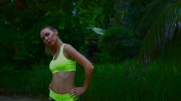 Fitness bella donna bionda nel giardino delle palme tropicali durante la bella giornata estiva — Video Stock