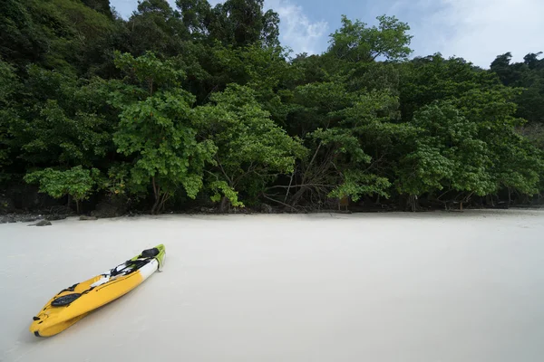 Un kayak giallo su una spiaggia tropicale su sfondo di alberi verdi — Foto Stock