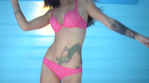 Happy bruneta krásná žena s úsměvem, skákání a tančí na posteli nad modré dřevěné zdi pozadí - video v pomalém pohybu. Zdravý život a odpočinek — Stock video