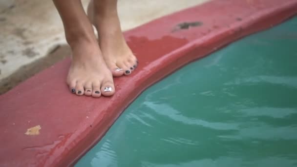 Primer plano de las piernas de la mujer de pie en el borde de la piscina y poner los pies en el agua — Vídeo de stock