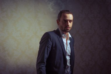 Genç, yakışıklı ve zarif bir adam klasik arka planda soyutlanmış poz veriyor.