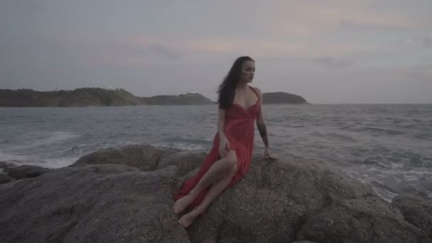 4k video al rallentatore di bella donna seducente in abito rosso che si diverte sulle rocce in riva al mare — Video Stock