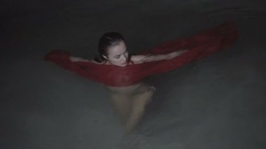 Güzel baştan çıkarıcı kadın gece açık havuzda kırmızı elbise giyiyor.