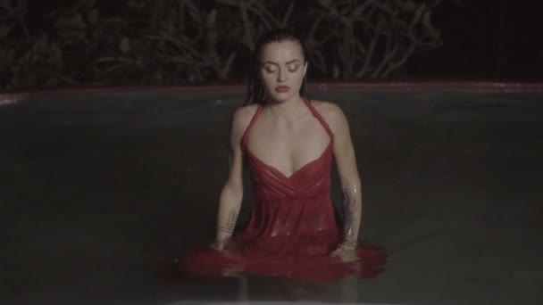 Bela mulher sedutora vestindo vestido vermelho na piscina ao ar livre à noite — Vídeo de Stock