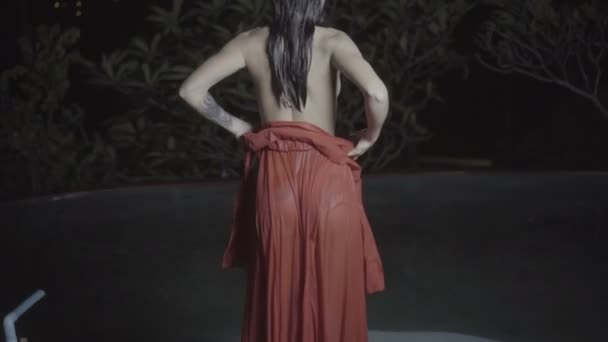 Bela mulher sedutora vestindo vestido vermelho na piscina ao ar livre à noite — Vídeo de Stock