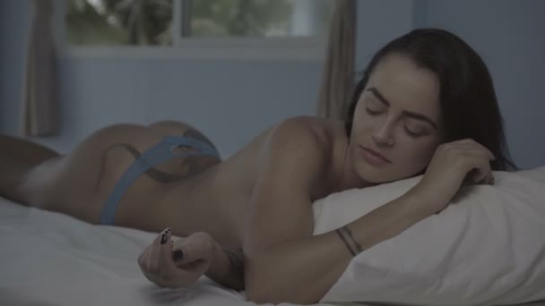 Schöne junge Brünette wacht friedlich auf, während sie auf ihrem Bett liegt — Stockvideo