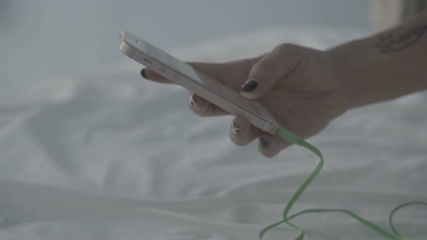 Mão mulher close-up usando seu smartphone e fones de ouvido na cama — Vídeo de Stock