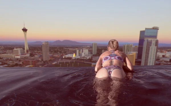 Vista trasera de la mujer rubia disfrutando de la vista de la ciudad de Las Vegas al atardecer desde la piscina infinita — Foto de Stock