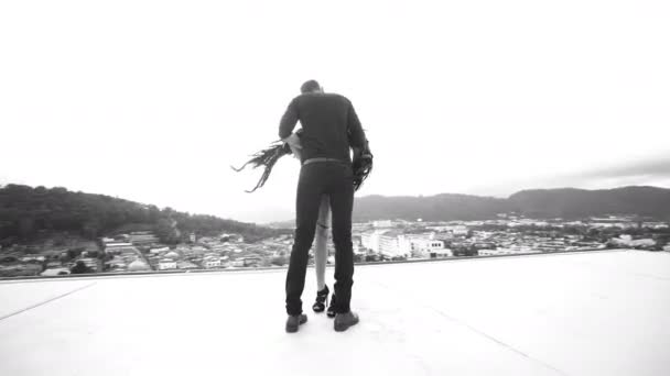 Vidéo en noir et blanc d'un baiser romantique entre l'homme et une femme ange sensuelle debout sur le toit au-dessus du ciel — Video