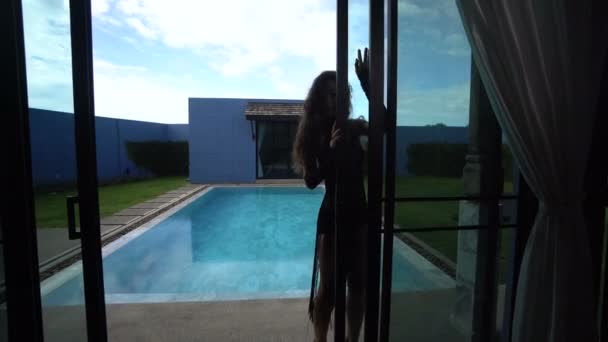 Vídeo de verano de una hermosa mujer de moda con cabello oscuro en elegante atuendo posando y bailando junto a la piscina en una lujosa villa — Vídeo de stock