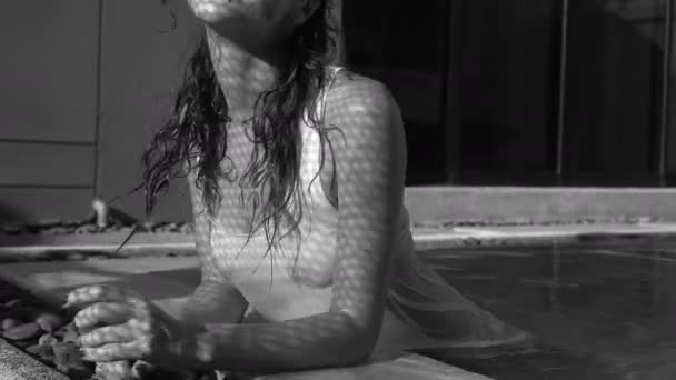 Black and white closeup portrait of beautiful happy brunette woman posing and smiling in the outdoor swimming pool during sunny summer day with shadow net reflection on her face and body — Stock Video