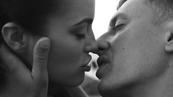 Zwart-wit close-up video van romantische kus tussen paar over hemelachtergrond — Stockvideo