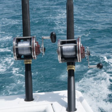 Mavi deniz üzerinde bir tekne balıkçılık çubuklar. Kutup sahipleri arkadaki bir teknenin içinde iki balıkçılık çubuklar resmini