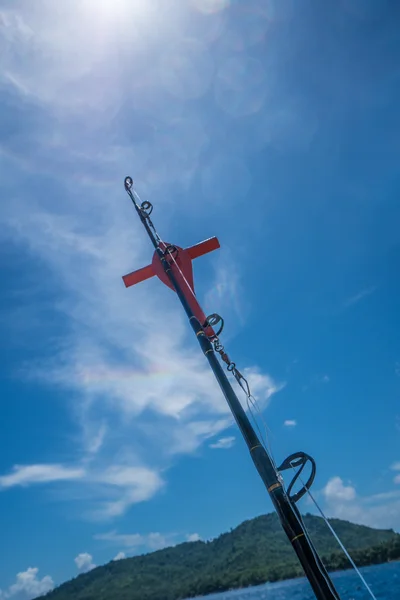 青い空と緑の島でボートに乗って釣りロッドのトップ。ボートの後ろにポール ホルダーにトップの釣り竿の画像 — ストック写真