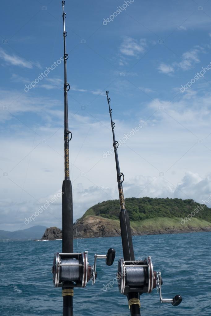 Fishing rods on a boat over blue sea, sky and green island