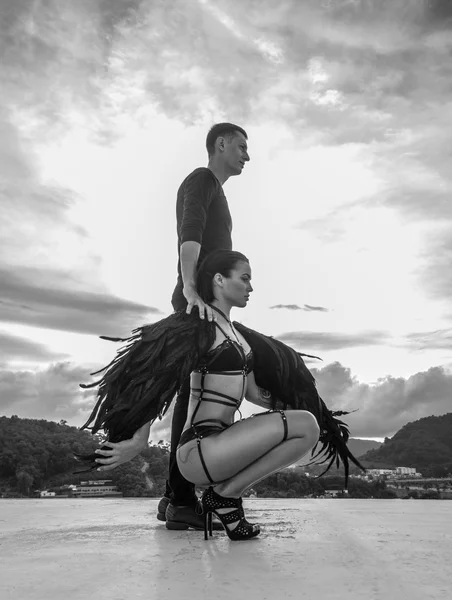 Черно-белое фото романтической сцены с мужчиной и чувственной женщиной-ангелом, стоящей на крыше над небом — стоковое фото