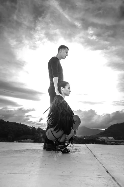 Foto en blanco y negro de la escena romántica con el hombre y la mujer ángel sensual de pie en la azotea sobre el fondo del cielo — Foto de Stock