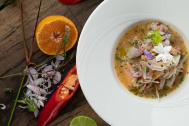 Karides, beyaz levrek, mürekkep balığı, portakal soslu somon, ahşap masada izole edilmiş.