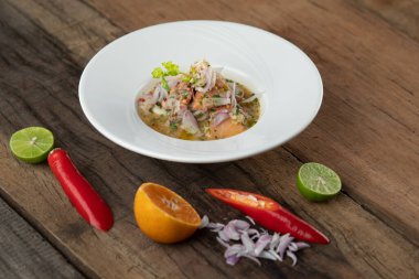 Karides, beyaz levrek, mürekkep balığı, portakal soslu somon, ahşap masada izole edilmiş.