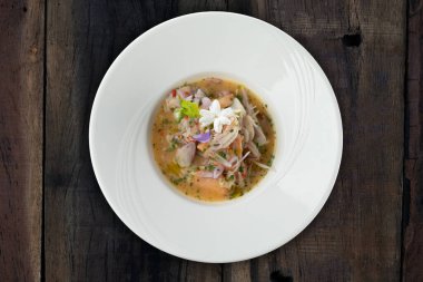 Karides, beyaz levrek, mürekkep balığı, portakal soslu somon, ahşap masada izole edilmiş.