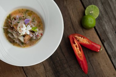 Karides, beyaz levrek, mürekkep balığı, portakal soslu somon, ahşap masada izole edilmiş.