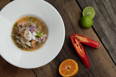 Karides, beyaz levrek, mürekkep balığı, portakal soslu somon, ahşap masada izole edilmiş.