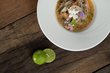 Karides, beyaz levrek, mürekkep balığı, portakal soslu somon, ahşap masada izole edilmiş.