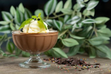 Tahta masanın üzerinde çikolatalı mus manzarası var. Koyu çikolata, yumurta, krema ve yaban mersinli koyu romlu tatlı.