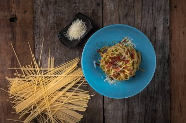 Geleneksel İtalyan makarna tabağı, domuz pastırmalı spagetti carbonara, yumurta sarısı, ahşap bir tabakta parmesan peyniri.