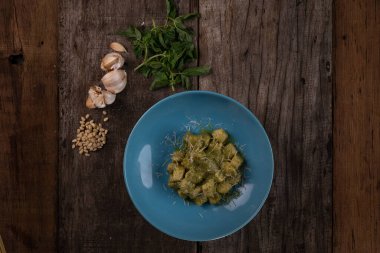 Ev yapımı pesto soslu gnocchi, parmesan ve fesleğen ahşap masada izole edilmiş.