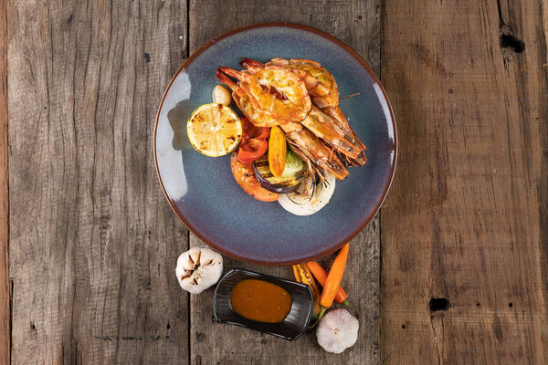 Top view of wok-fried prawns with garlic and chili isolated on wooden rustic table