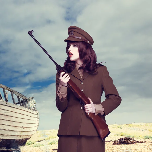 Atractiva mujer en uniforme del ejército llevando un rifle Imagen De Stock