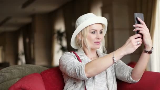 Frau macht Selbstporträt im Hotel und teilt Fotos aus dem Urlaub mit Hut