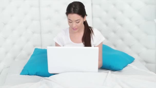 Όμορφη γυναίκα χρησιμοποιώντας ένα φορητό υπολογιστή που κάθεται στο κρεβάτι — Αρχείο Βίντεο