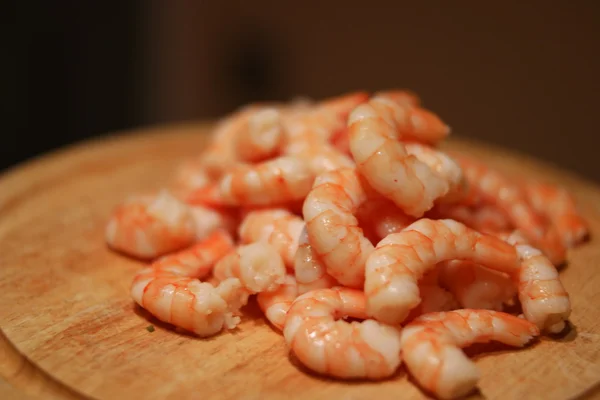 Camarones cocidos en la parte superior de la tabla de cortar de madera — Foto de Stock