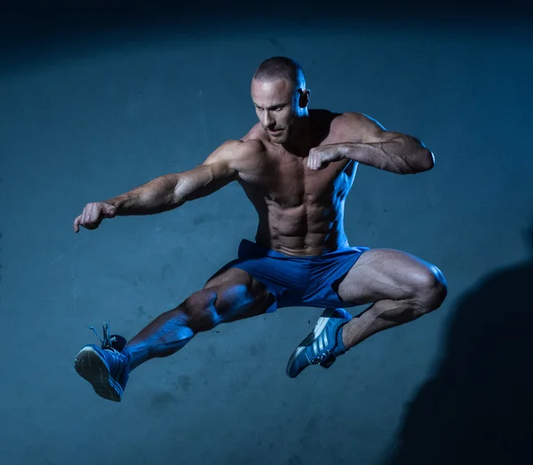 Sportlicher junger Mann in fliegender Kampfkunst-Pose — Stockfoto