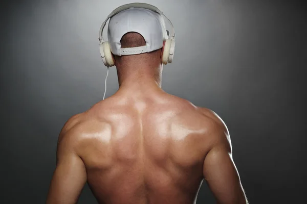 Visão traseira do homem muscular com tampão e fones de ouvido — Fotografia de Stock