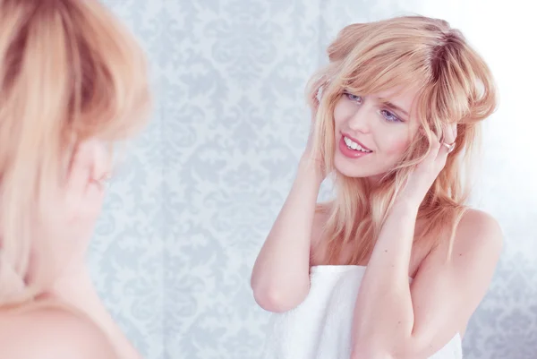 Jovem Sorrindo Mulher Tousling Cabelo no Espelho — Fotografia de Stock