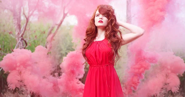 Femme aux cheveux roux portant une robe entourée de fumée — Photo