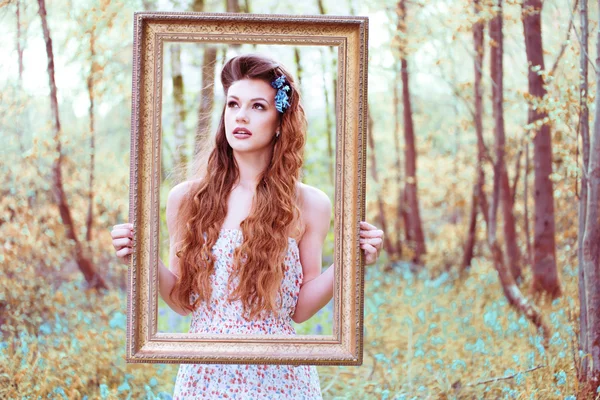 Mujer encantadora mirando a través de un marco de retrato —  Fotos de Stock
