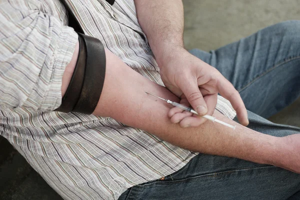 Hombre inyectándose a sí mismo con una pequeña hipodérmica — Foto de Stock