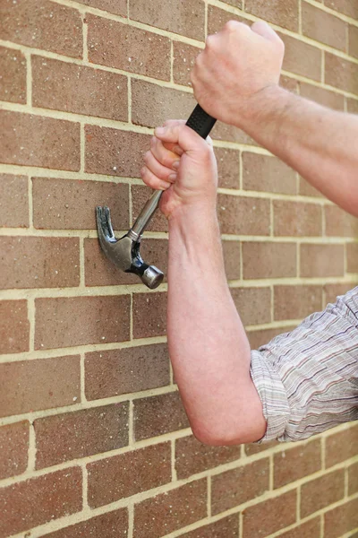 Un homme heurte un mur de briques avec un marteau — Photo