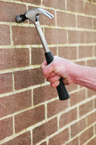 Un homme heurte un mur de briques avec un marteau — Photo