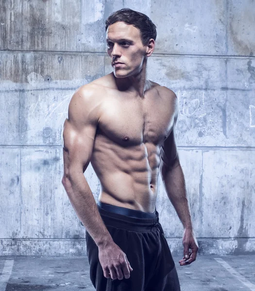 Fitness male model in old garage — Stock Photo, Image