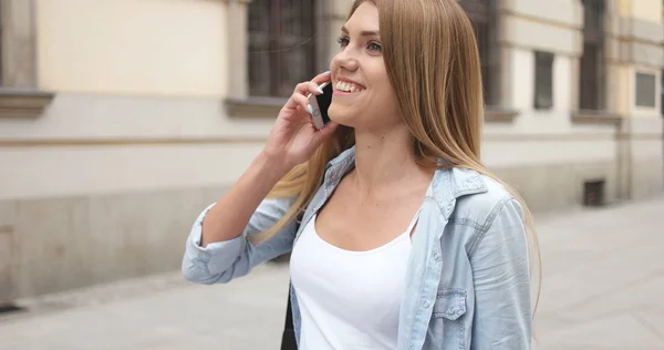 Giovane donna con telefono a piedi per strada — Foto Stock